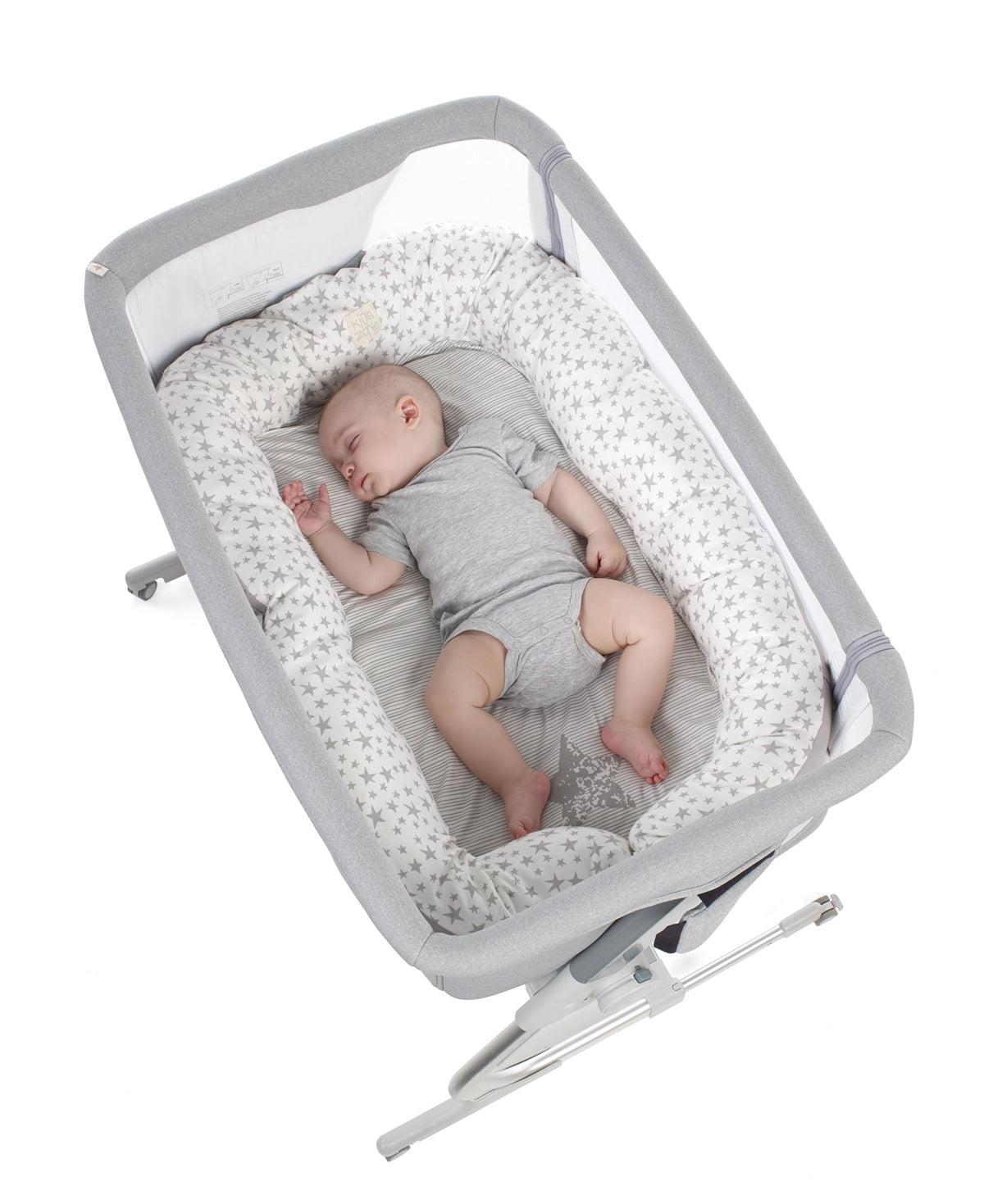Baby sleeping in a gray crib with white bedding on a white background