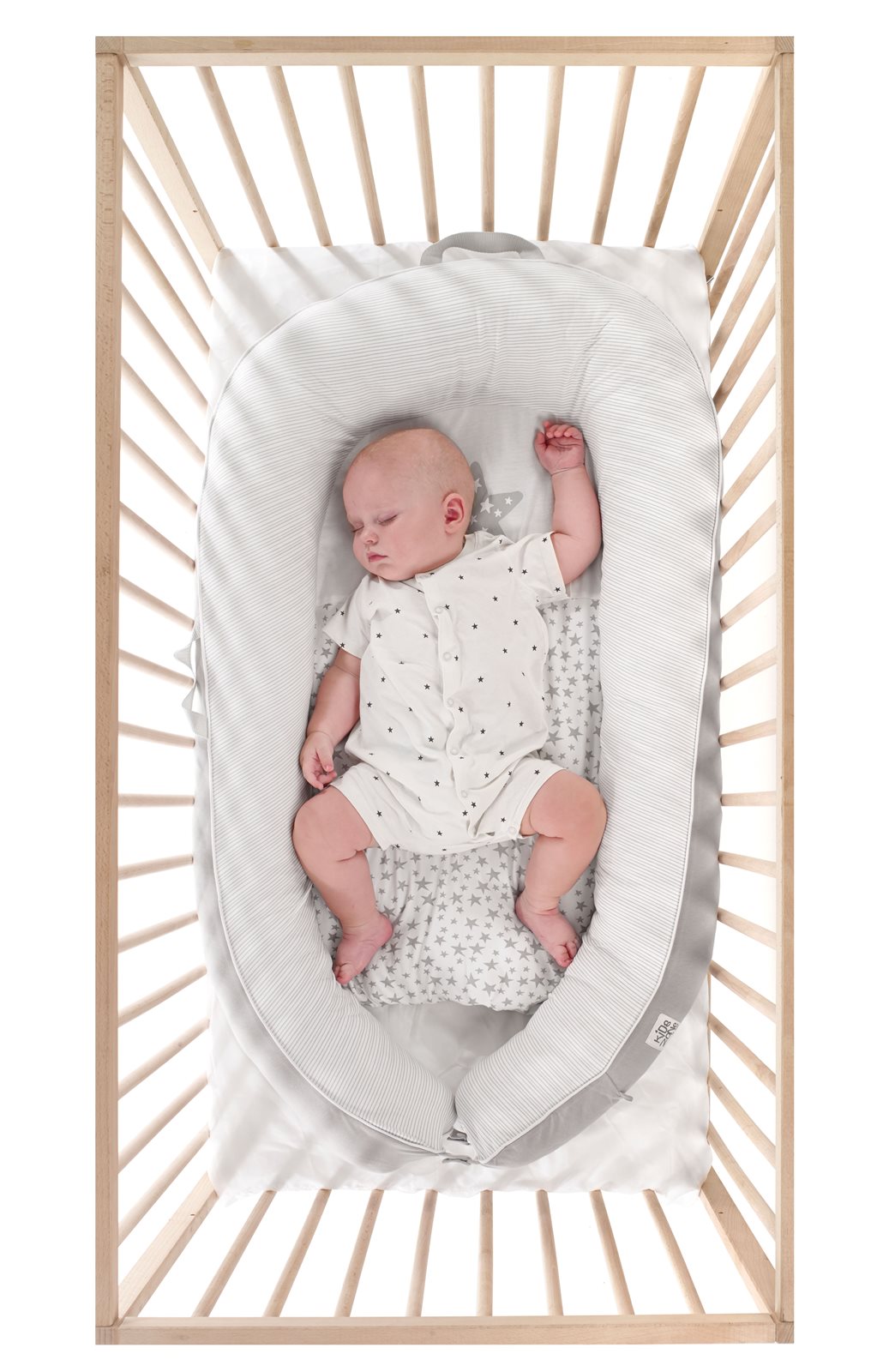 Baby sleeping in a wooden crib with white bedding