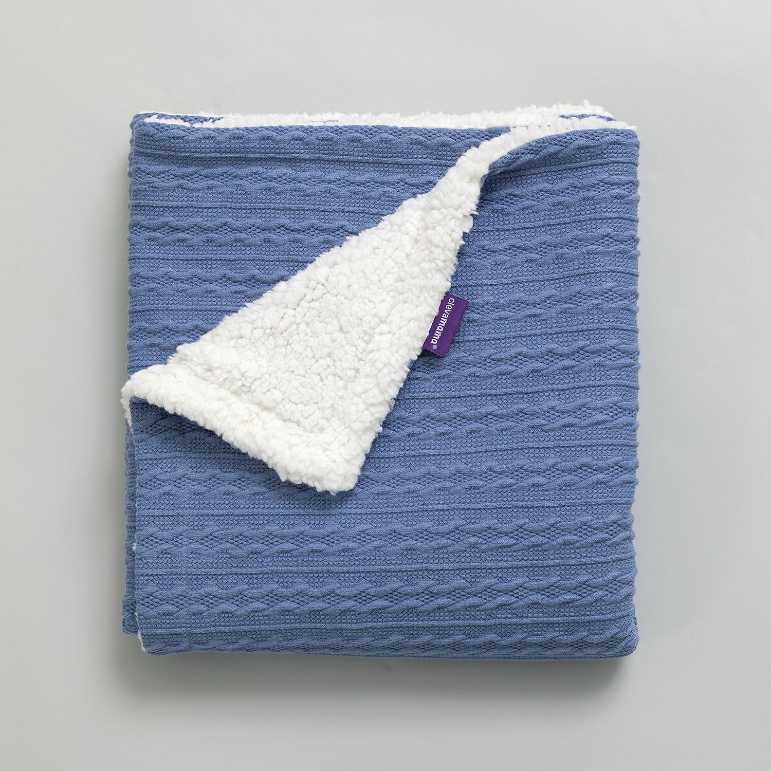 Blue textured blanket with white sherpa lining on a gray background