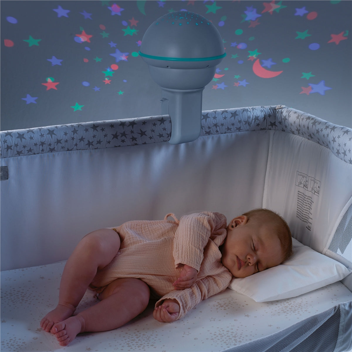 Baby sleeping in a crib with a starry night light projector on the wall.