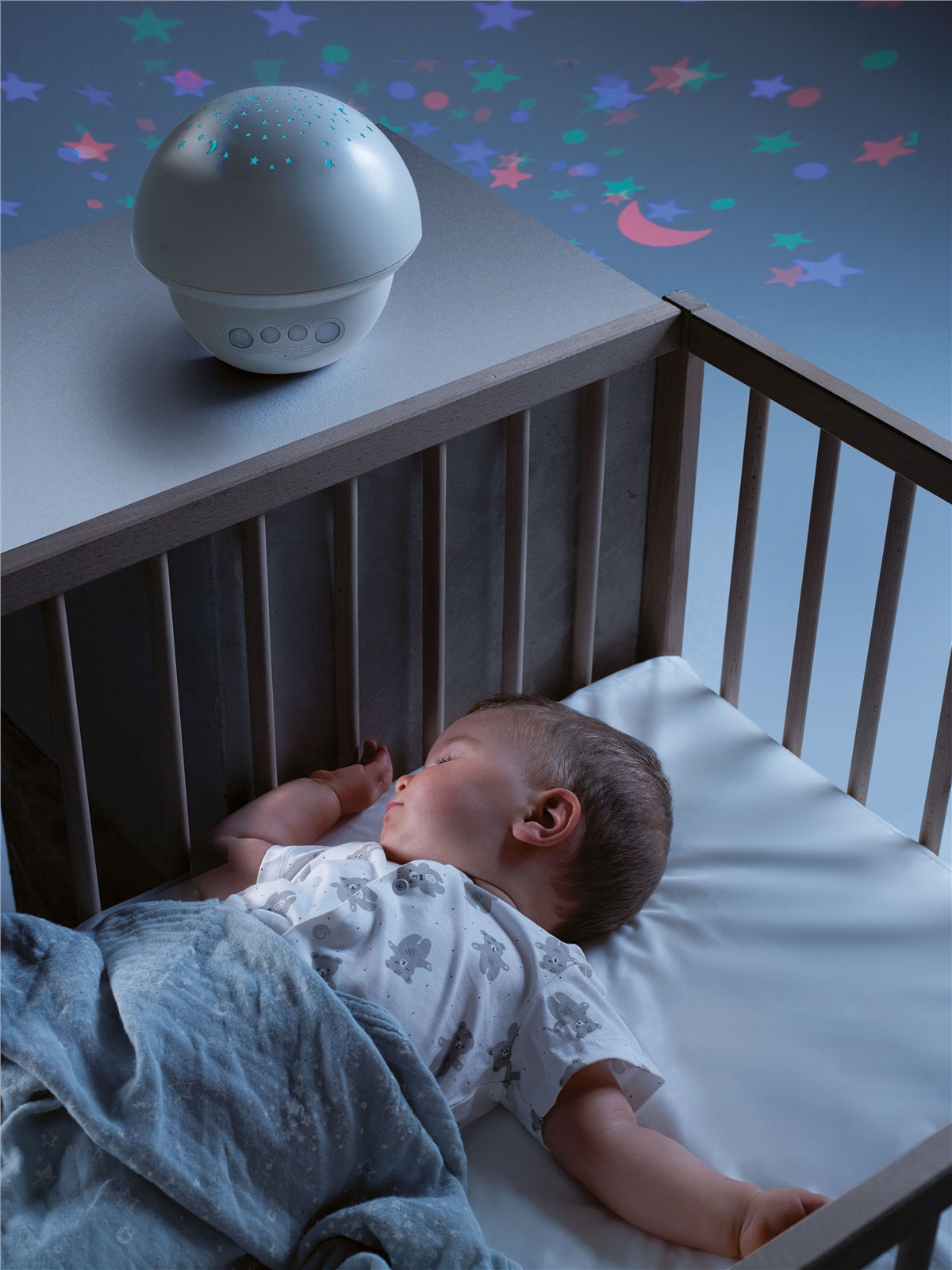Baby sleeping in a crib with a starry night light above