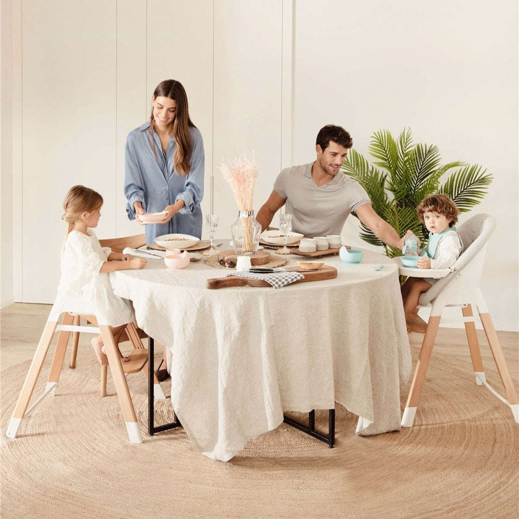 Family of four sitting around a dining table in a bright, minimalistic room.
