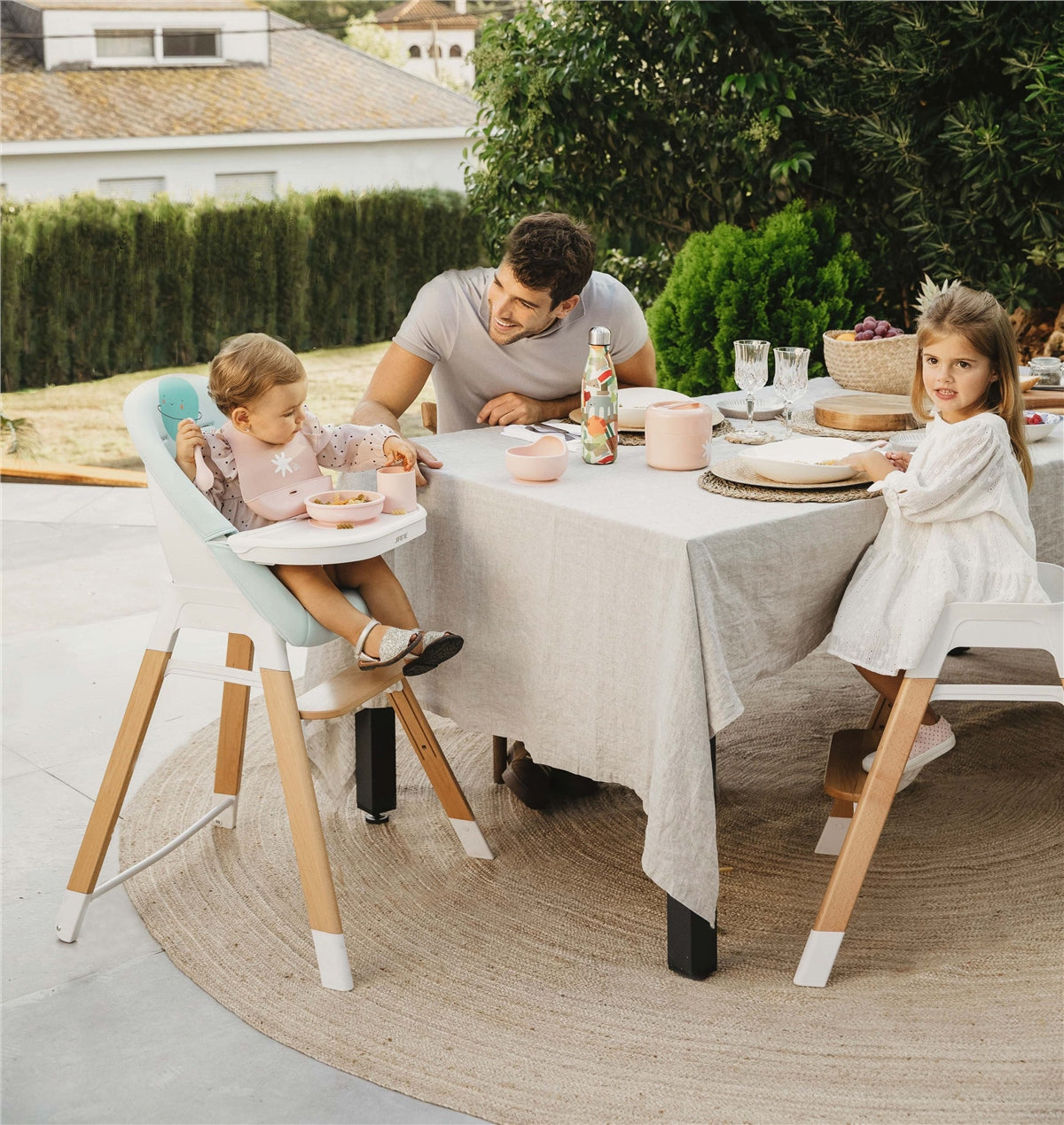 Family dining outdoors with children using high chairs
