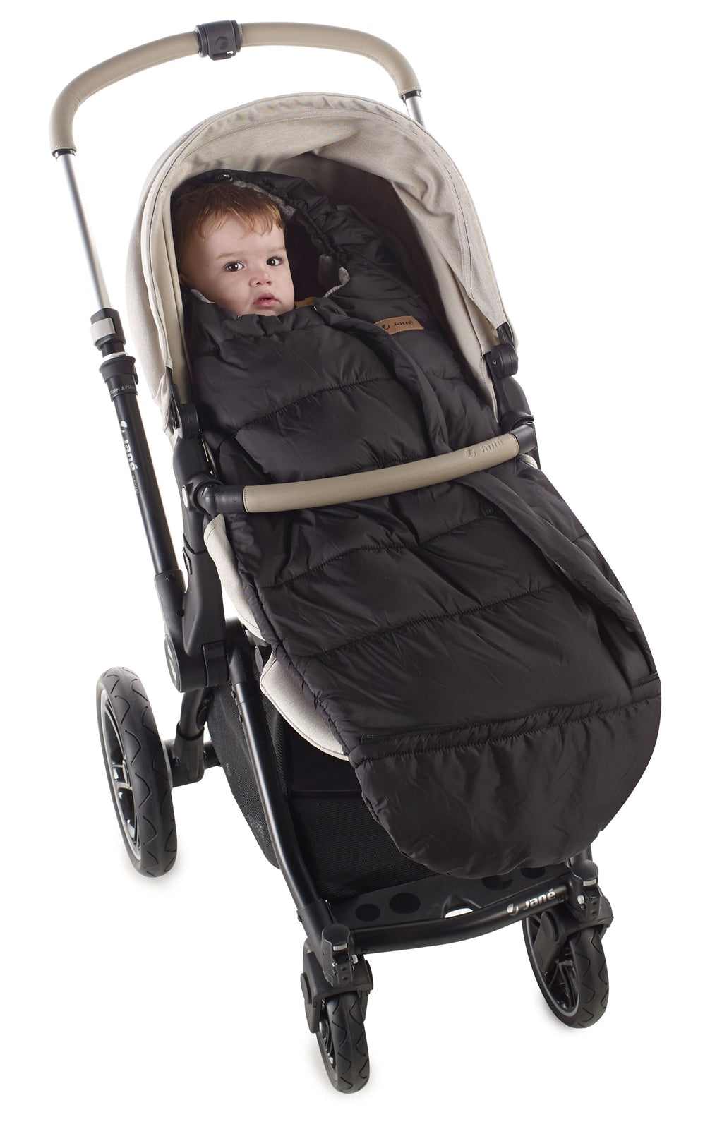 Baby in a stroller with a black footmuff on a white background