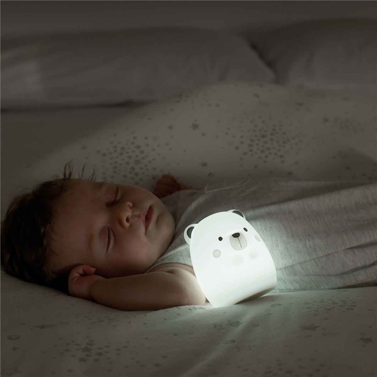 Baby lying in bed with a white bear-shaped night light