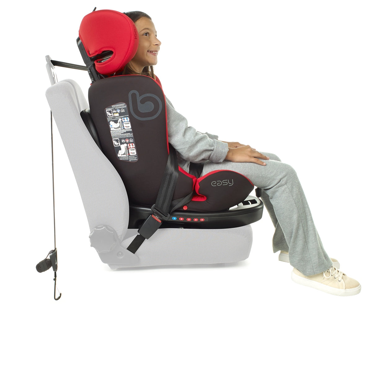 Child sitting in a booster car seat with a helmet on a white background