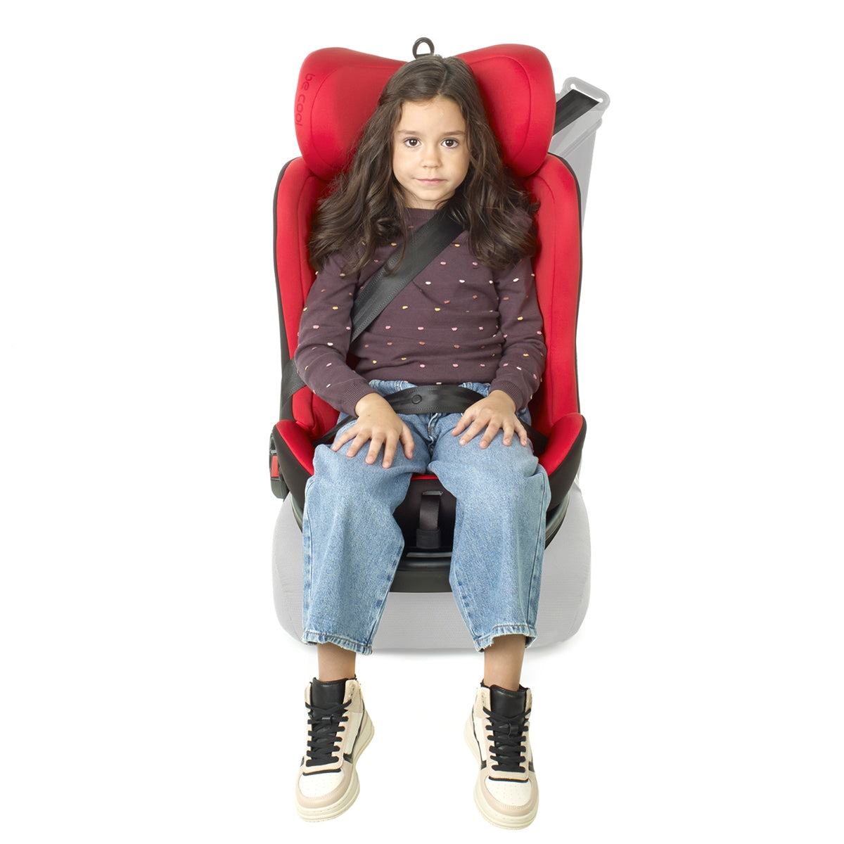 Child sitting in a red and gray car seat on a white background
