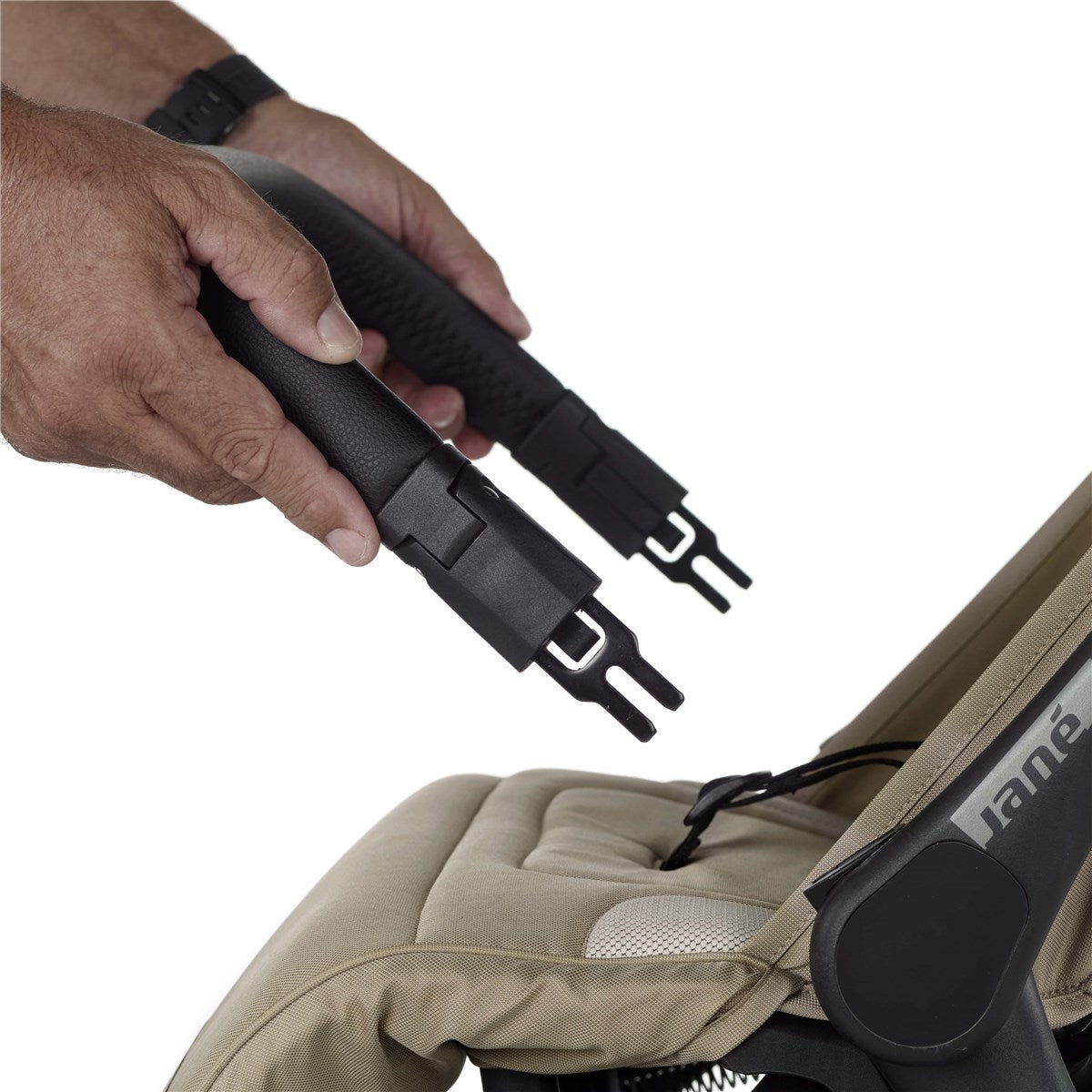 Hand adjusting a black stroller strap on a beige stroller with 'Jane' branding.