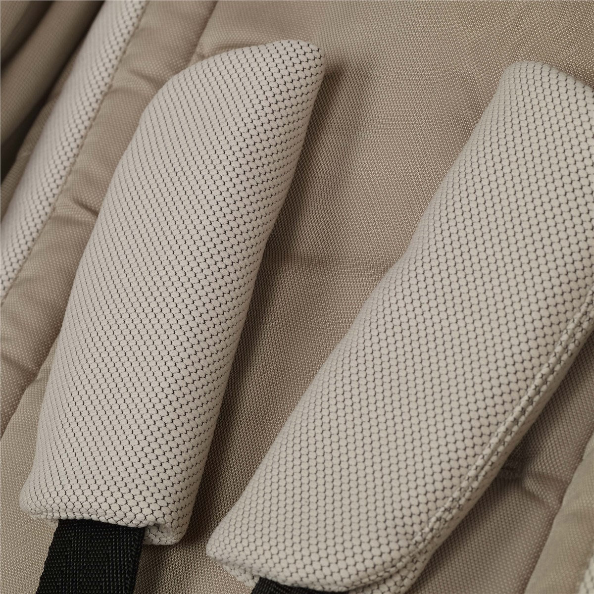 Close-up of beige stroller straps on a matching fabric background.