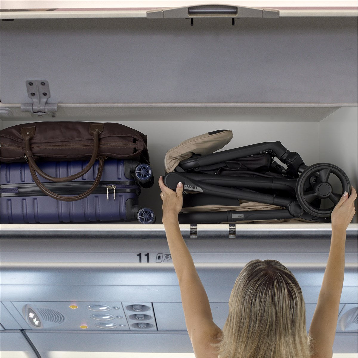Person loading a stroller into an airplane overhead compartment.