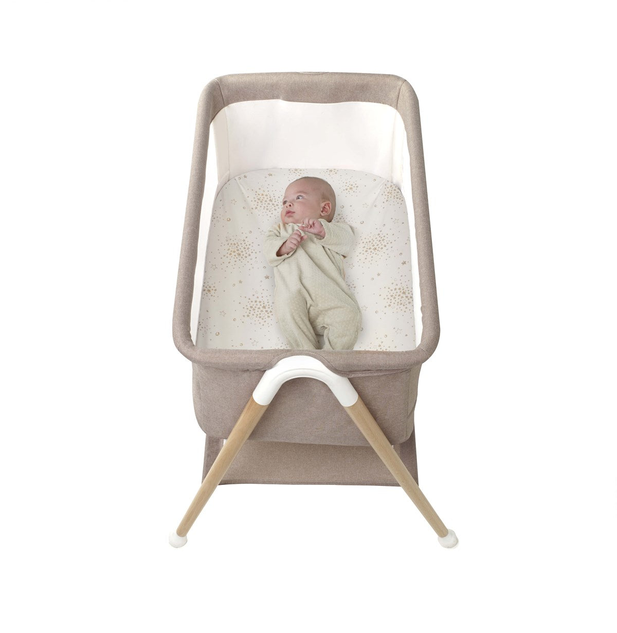 Baby in a beige bassinet with wooden legs on a white background