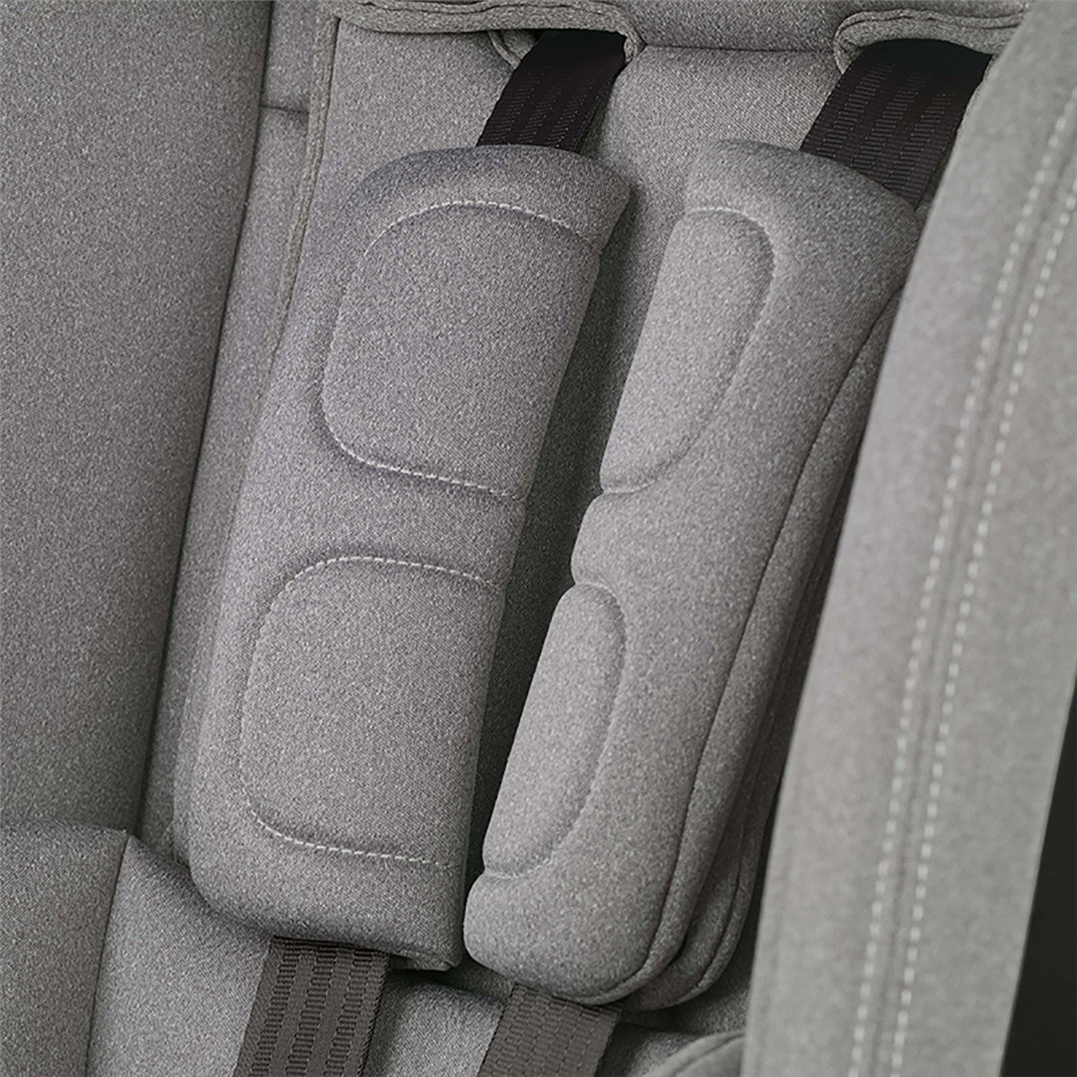 Gray car seat with headrests and straps in a vehicle interior.