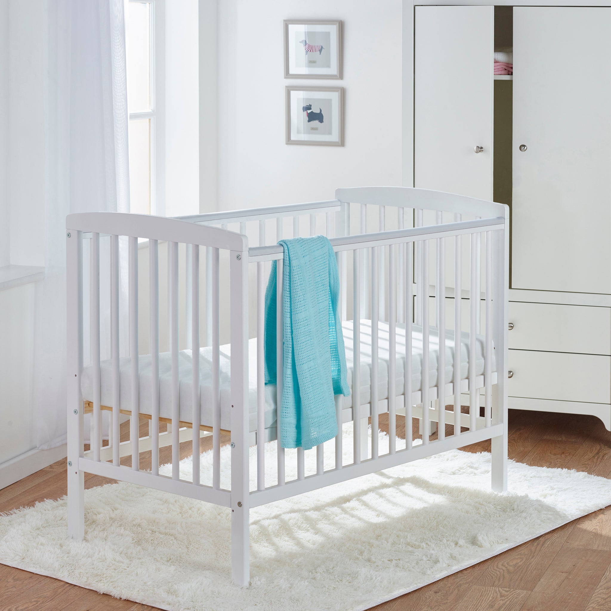 White cot with a blue blanket in a nursery setting