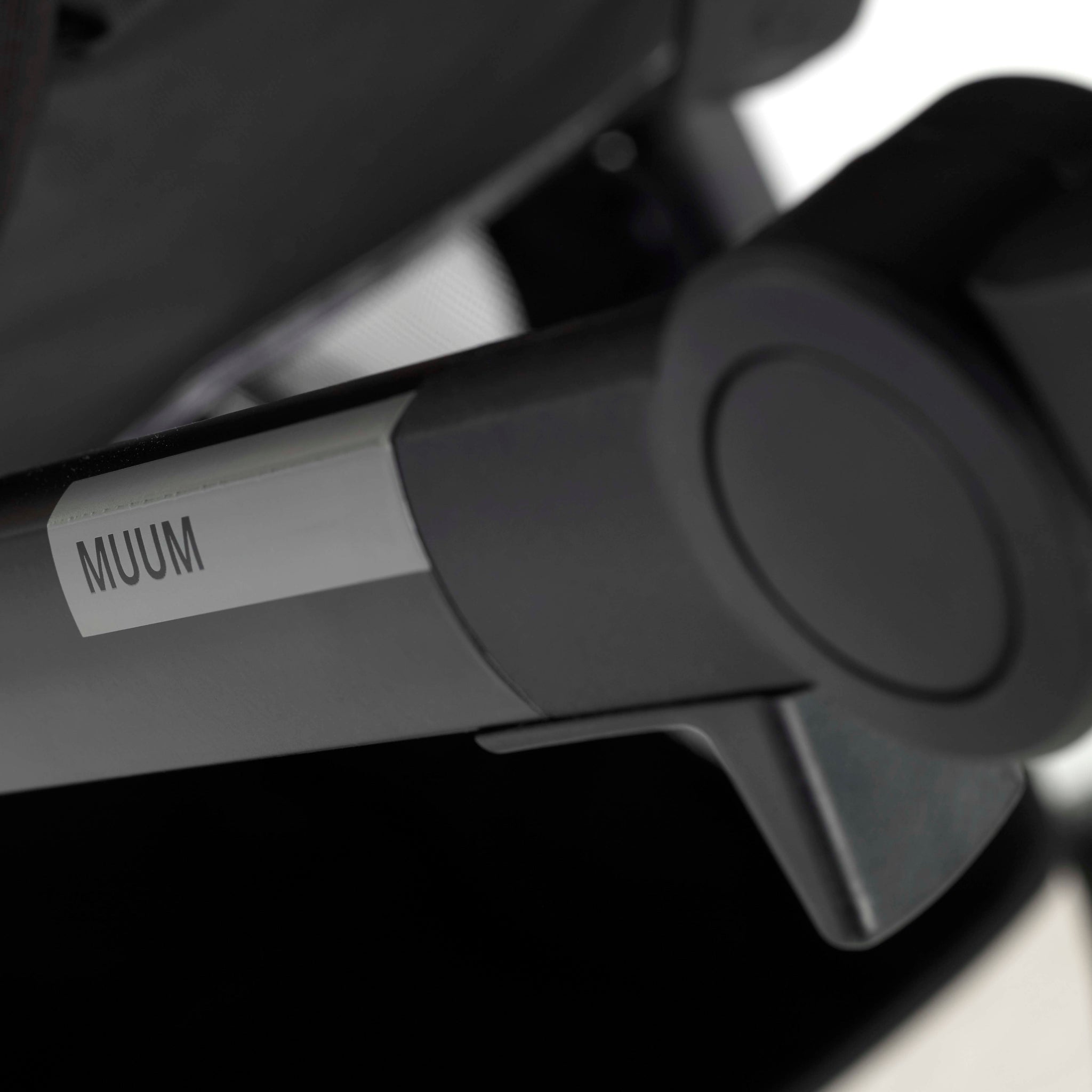 Close-up of a black and gray object with 'MUUM' label on a blurred background