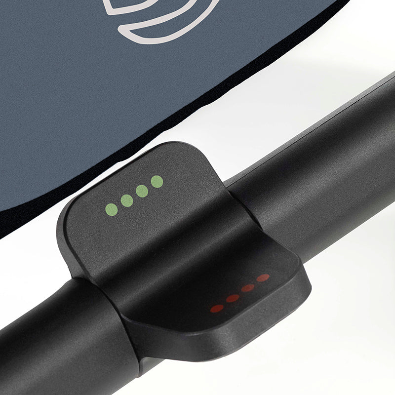 Close-up of a black stroller clip with green and red dots on a white background