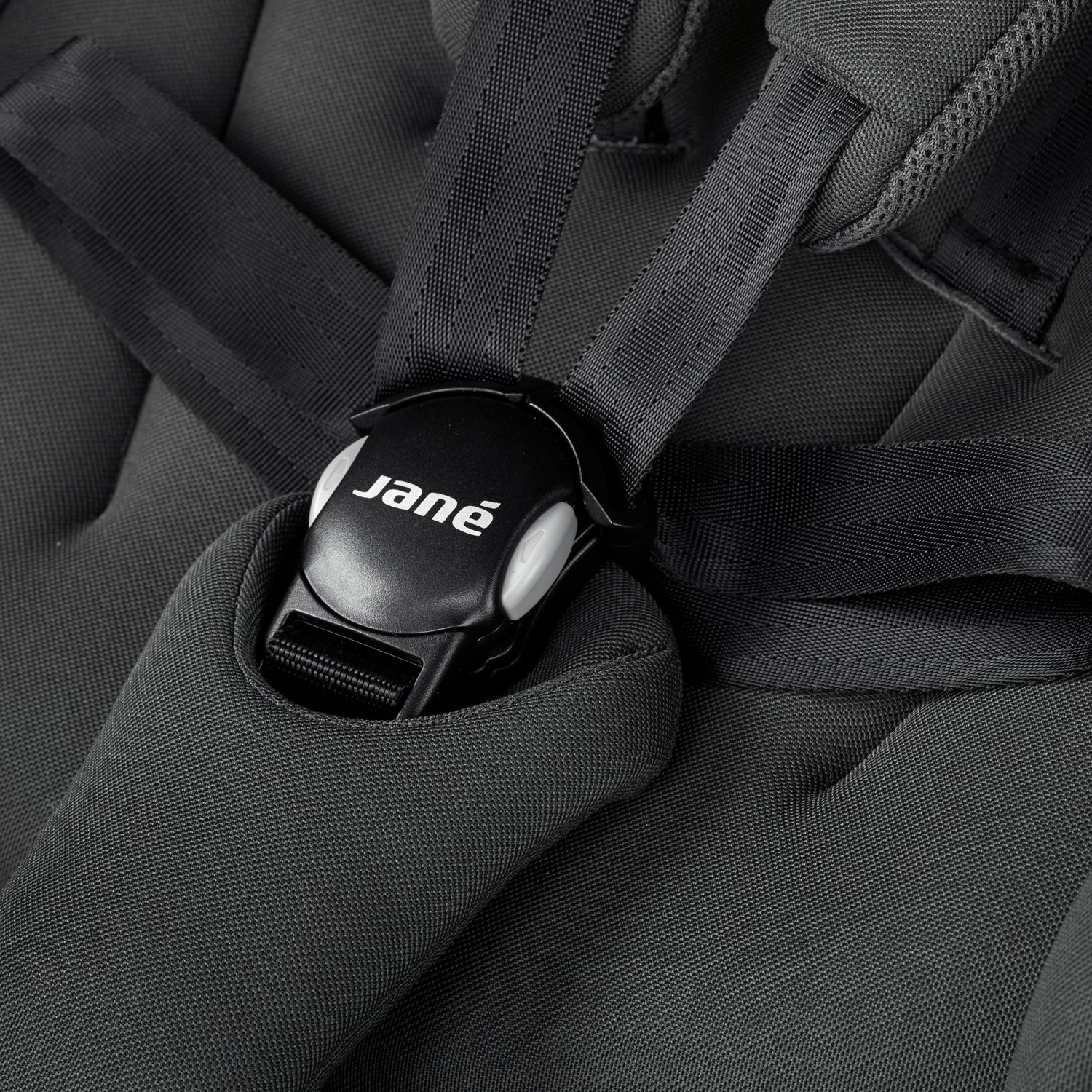 Close-up of a black car seat with a 'Jane' logo on the buckle.