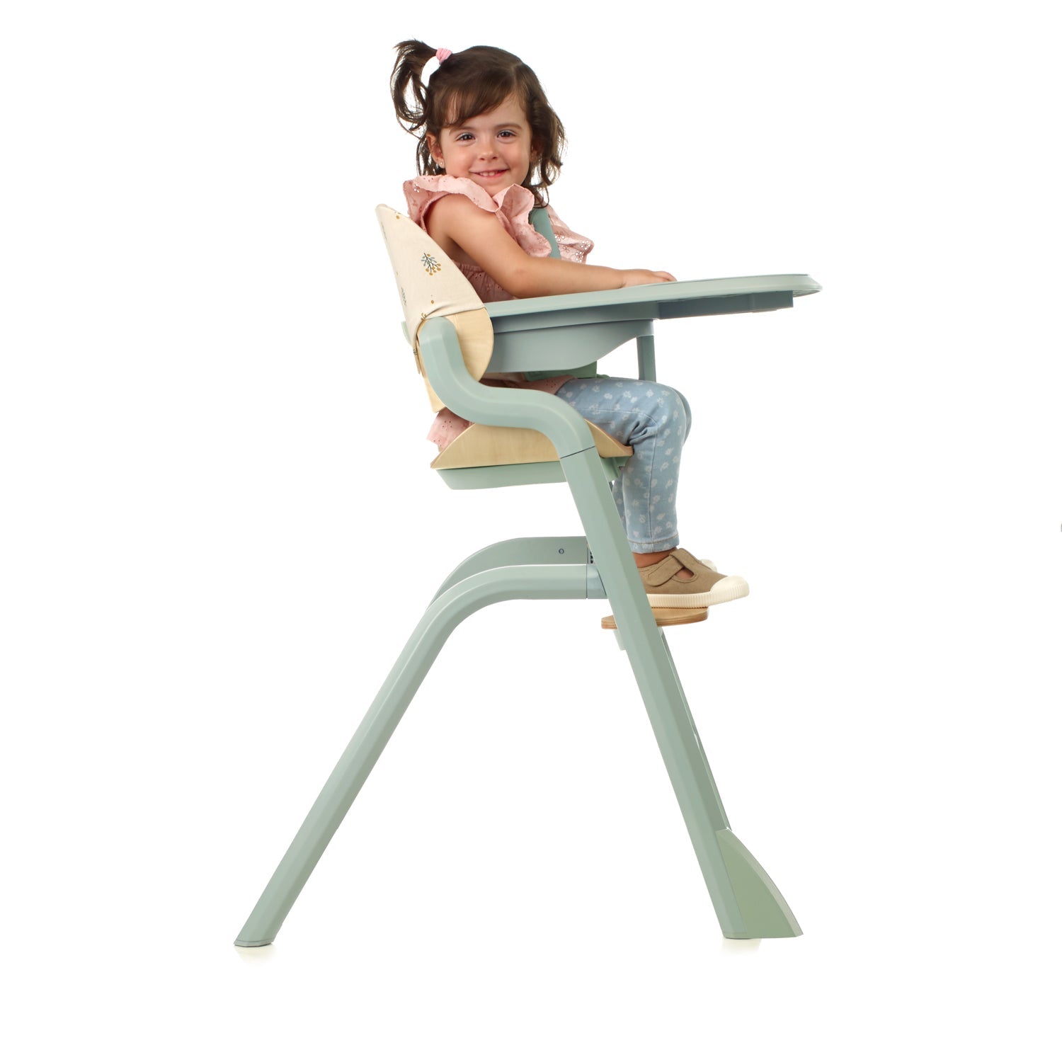 Child sitting in a green and beige high chair on a white background