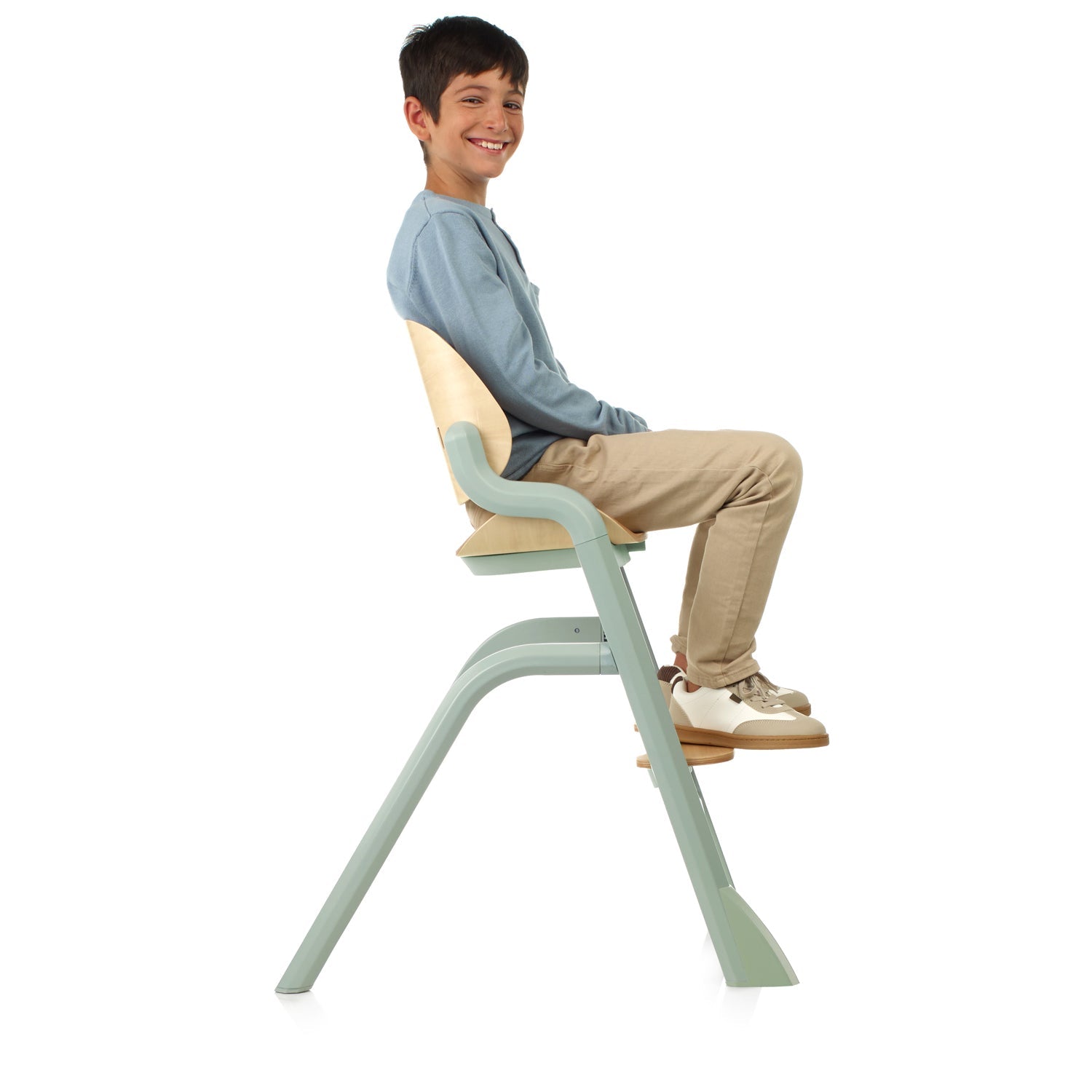Child sitting on a green adjustable chair against a white background