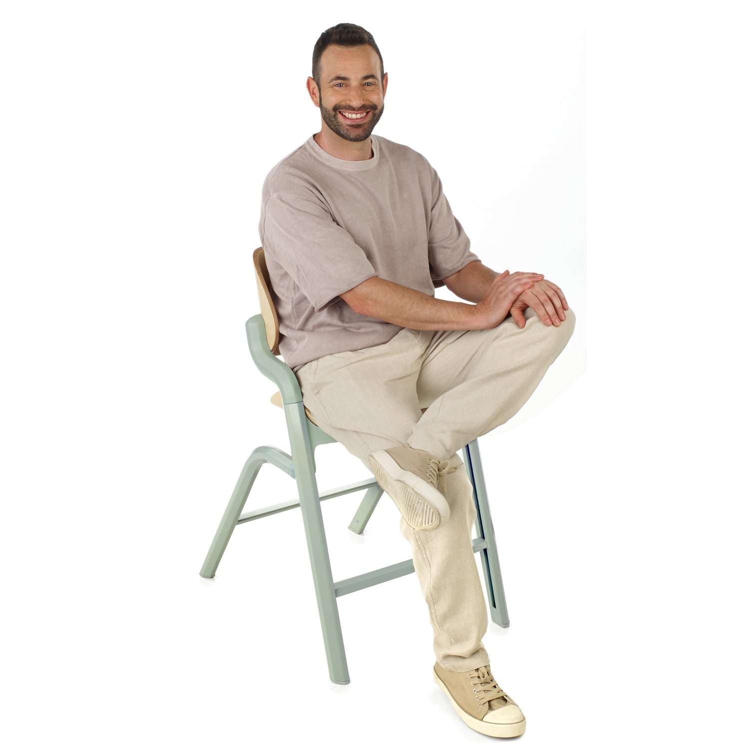 Man sitting on a light green stool against a white background