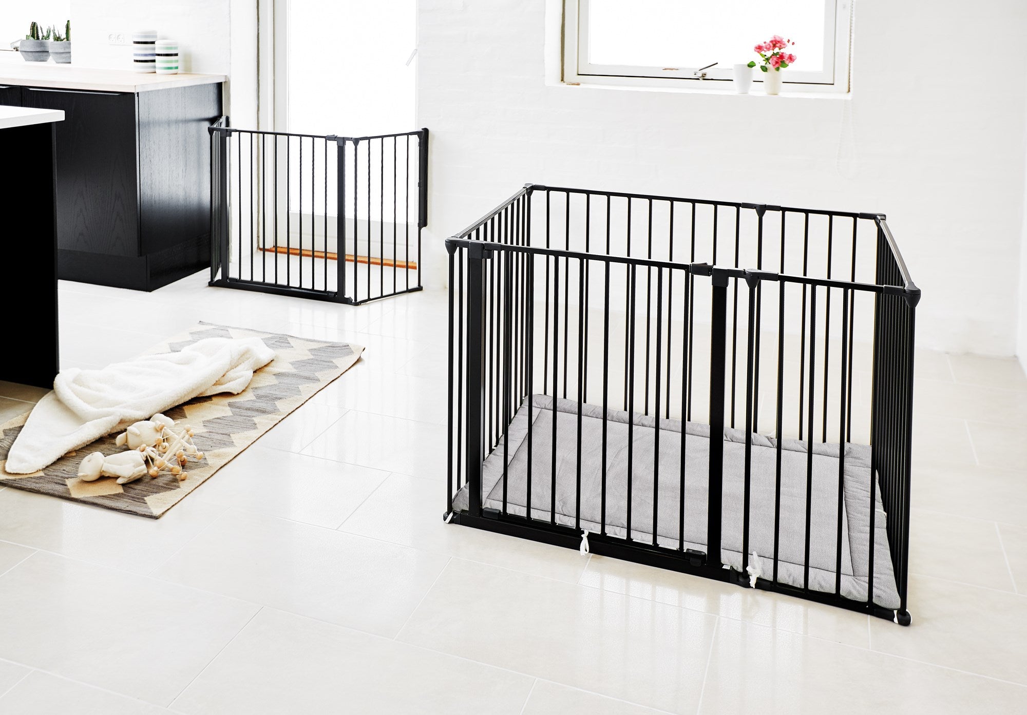 Black metal baby gate in a room with white walls and a rug.