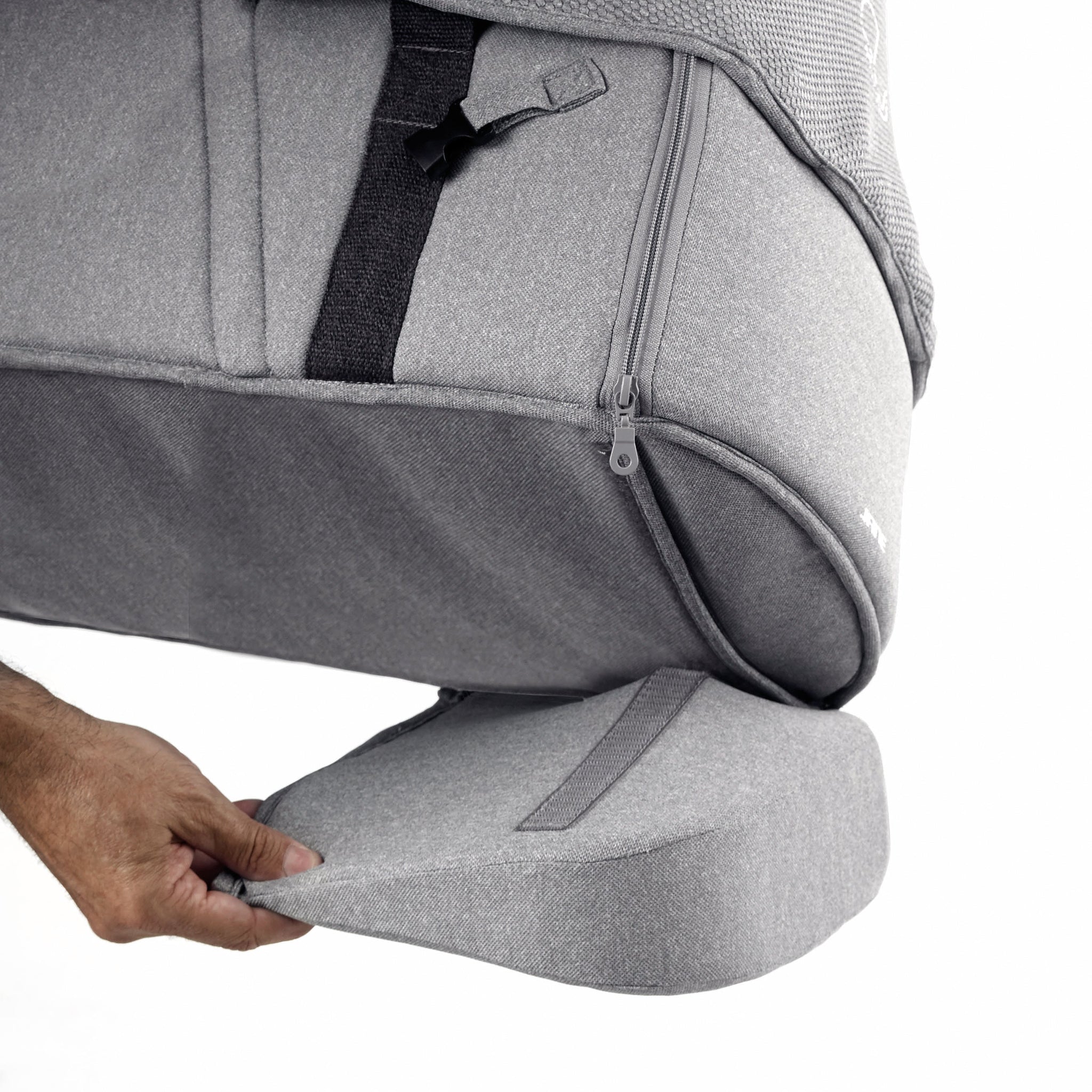 Gray carrycot on a person adjusting the back support pad on a white background