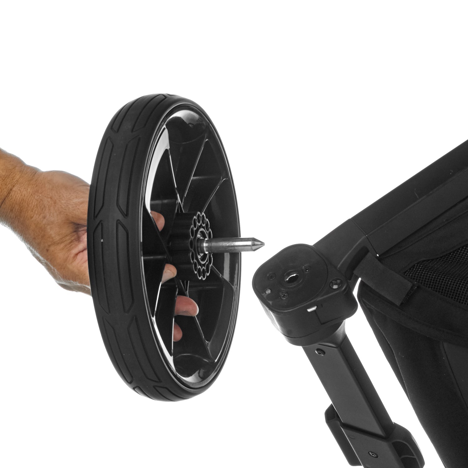 Close-up of a stroller wheel being removed from a stroller with a hand holding the wheel.