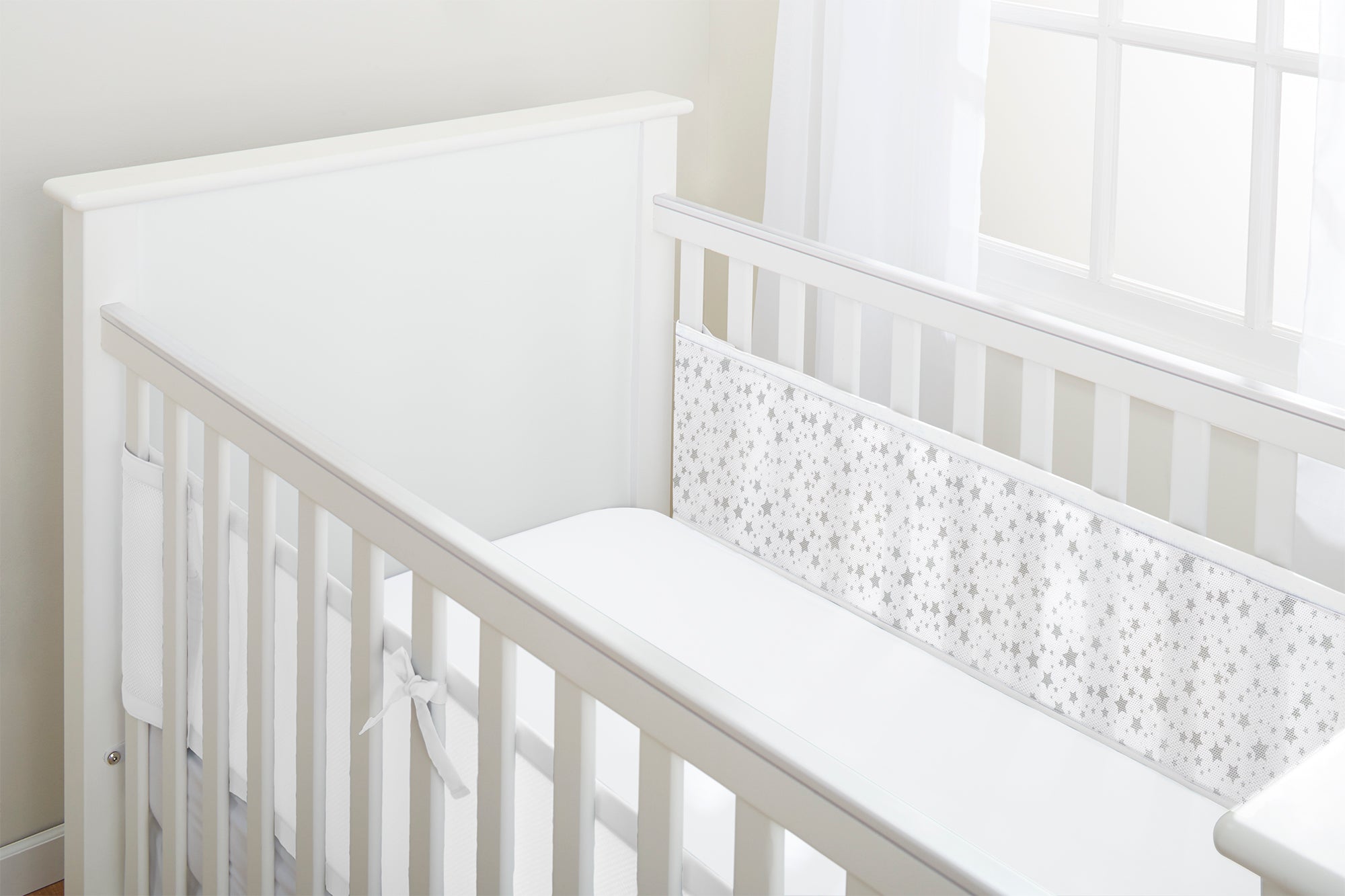 White crib with a star bumper pad in a bright room