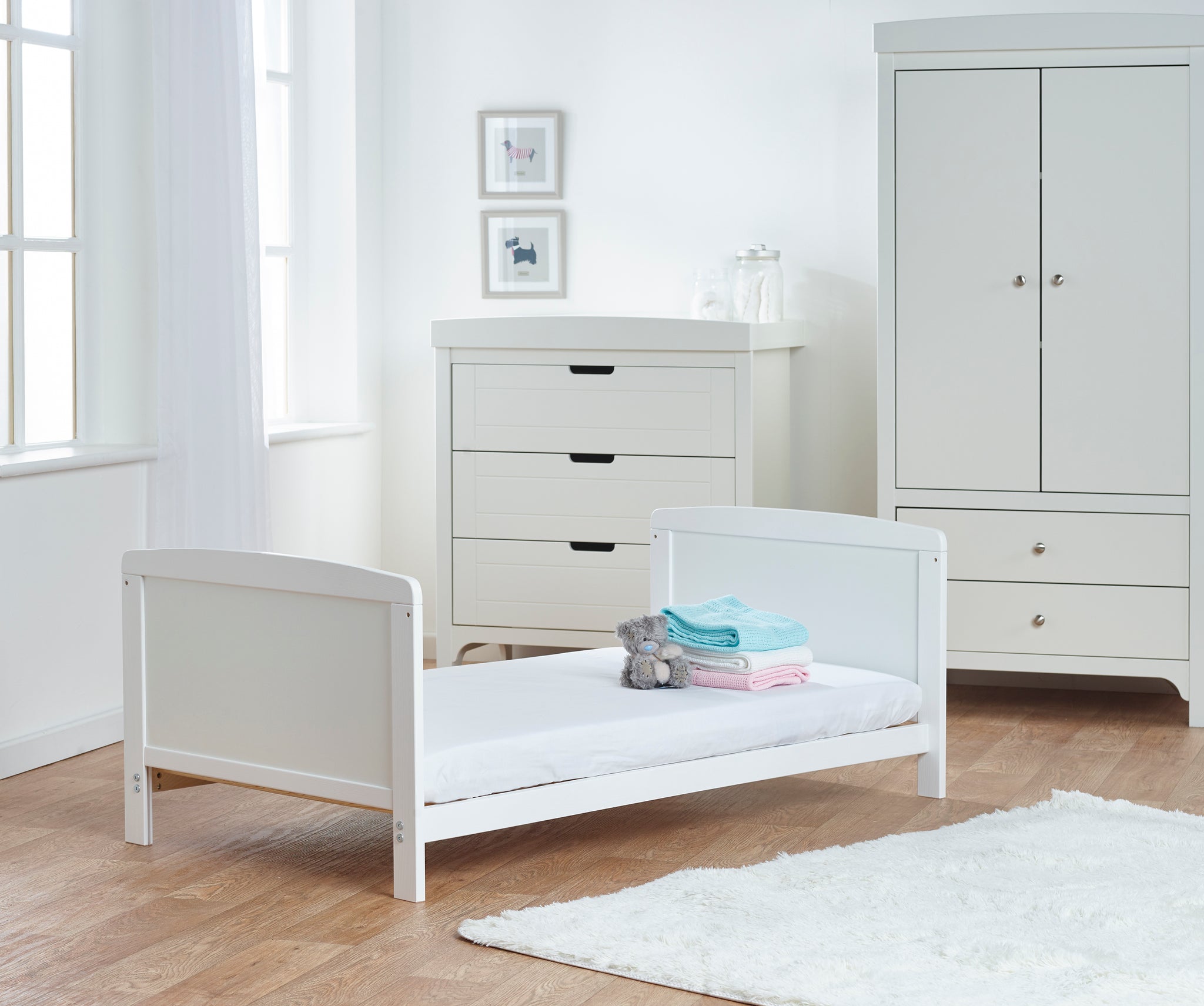 White children's bed in a room with white dresser and wardrobe