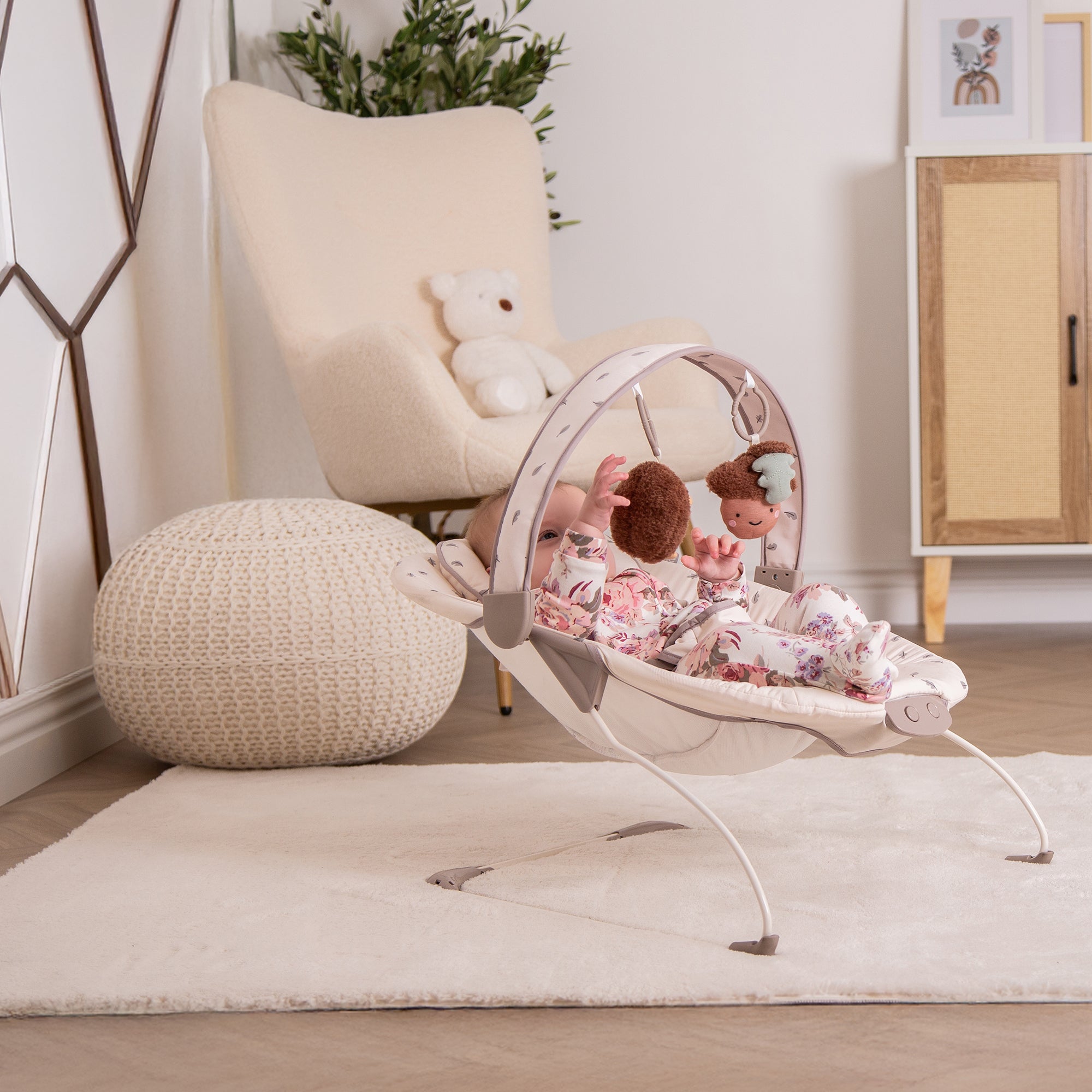 Baby bouncer with plush toys in a nursery setting