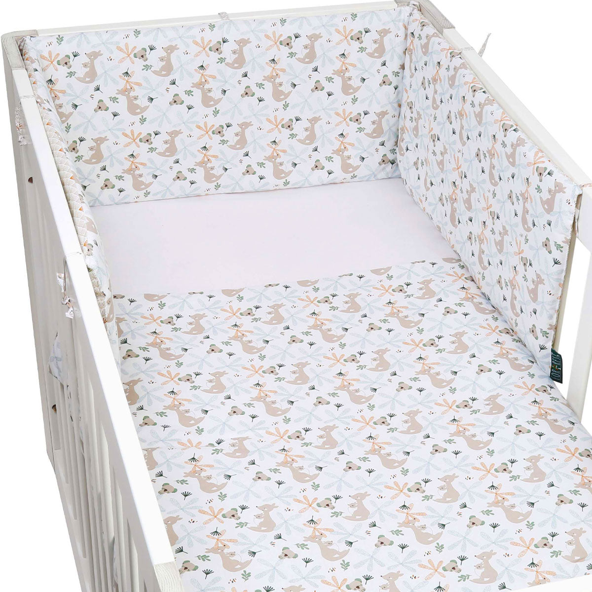 Crib with floral and animal patterned bedding on a white background