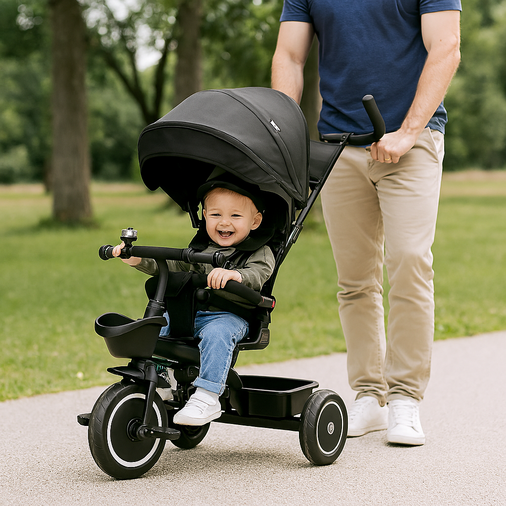 Child in a black tricycle being pushed by an adult in a park
