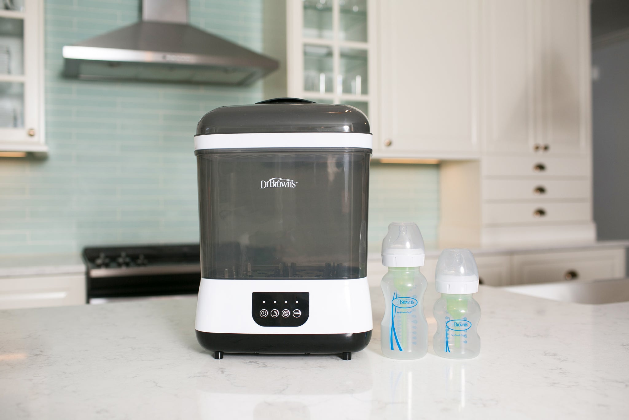 Baby bottle sterilizer on a kitchen counter with bottles beside it