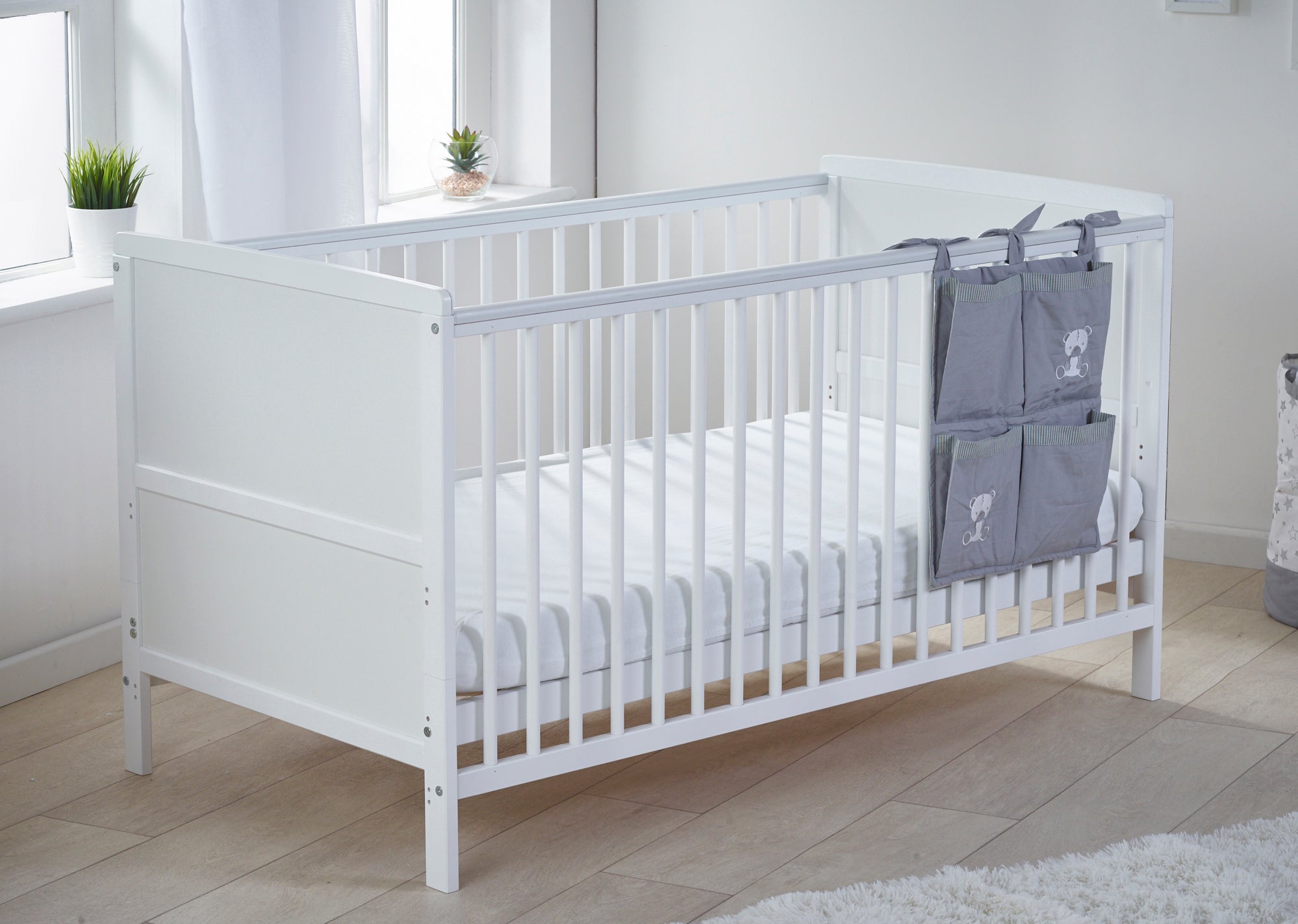 White cot with white bedding in a bright room