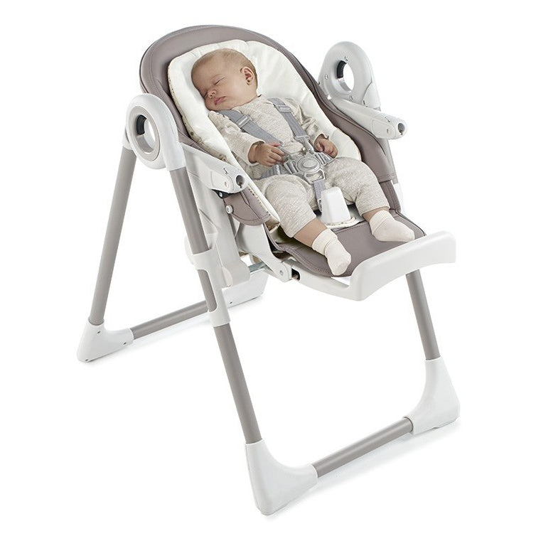 Baby in a gray and white baby highchair on a white background
